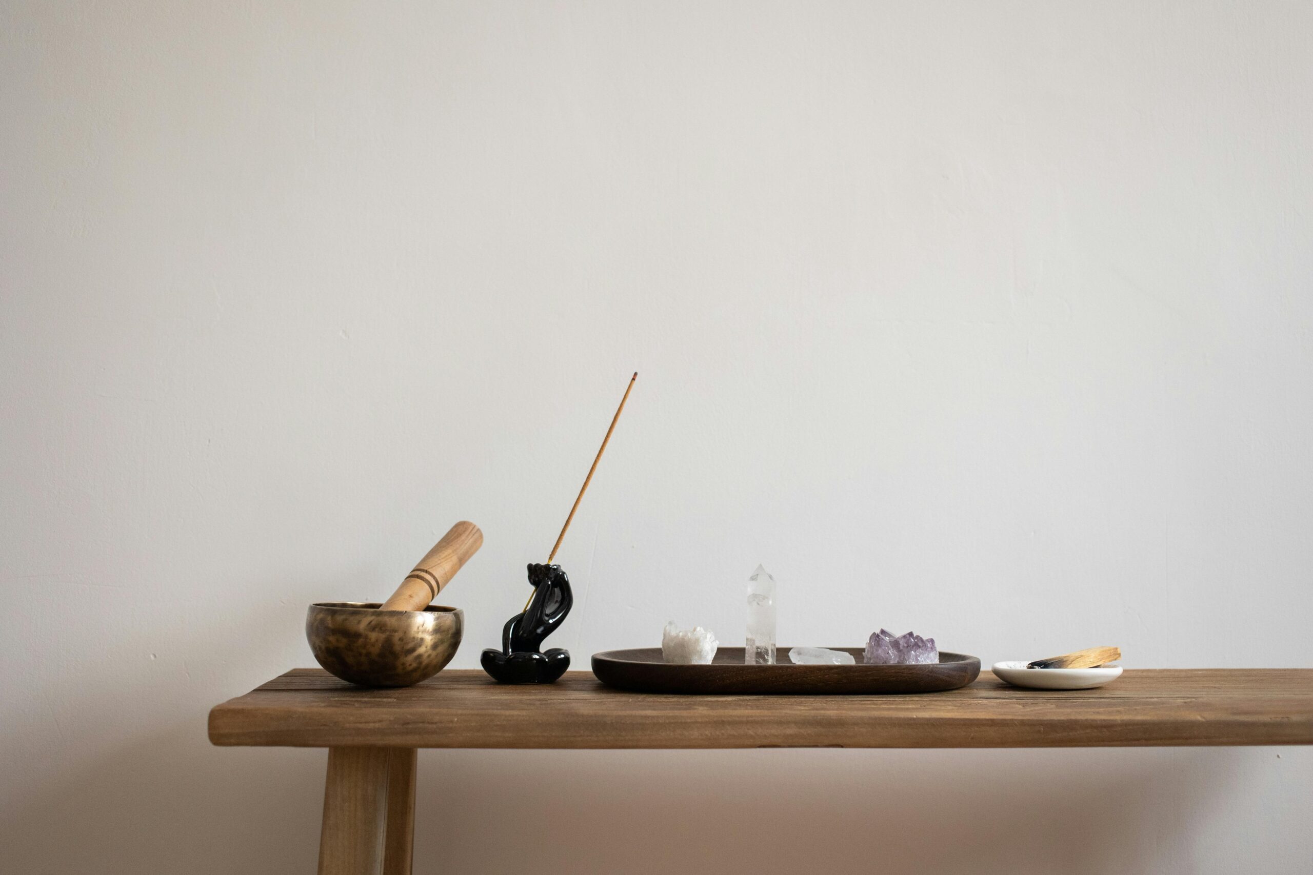 A serene setup featuring crystals, incense, and a singing bowl on a wooden table, perfect for meditation.